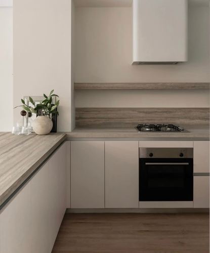 Minimalist L-shaped kitchen with stone-look backsplash, matte cabinetry, cooktop, oven and wood floor