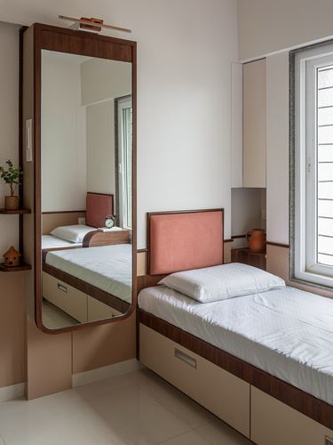 Bedroom corner with pink velvet headboard, wood-framed floor mirror, and beige storage bed under a window