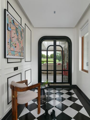 Foyer with black and white checkerboard floor, arched glass door, and colorful framed art