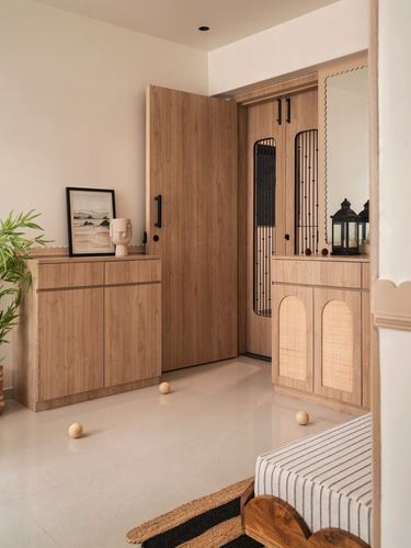Wooden foyer with scalloped mirror, cane-paneled cabinet, and black metal door screens
