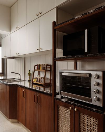 Galley kitchen with dark wood cabinetry, cream upper cupboards, and open shelving holding a microwave and toaster oven