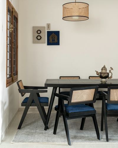 Dining table with black cane chairs, indigo cushions, and a rattan drum pendant light