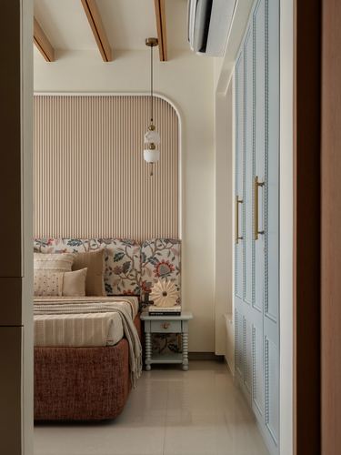 Bedroom with arched fluted headboard, floral bedding, pendant light, and pale blue paneled wardrobe
