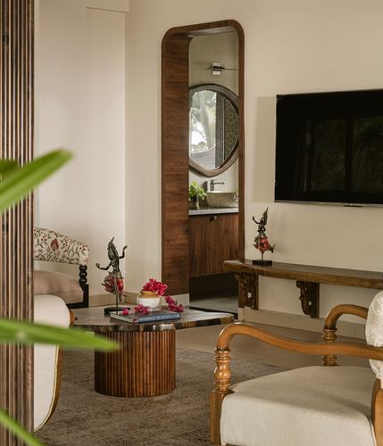 Living room with fluted wooden coffee table, arched mirror leading to a wash area, and console below a mounted tv