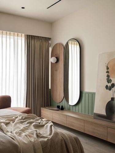 Bedroom corner with oval mirror, wood accent panel, sage wainscoting and low wooden console