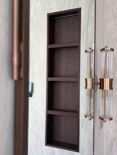 Recessed wood shelving niche beside a mirrored panel with dual brass fluted glass sconces