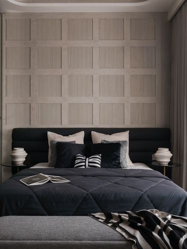 Bedroom with dark upholstered bed against a grid-patterned fluted plaster wall