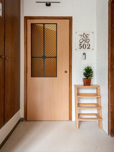 Entrance door with diagonal glass lattice beside white brick wall and apartment nameplate 502
