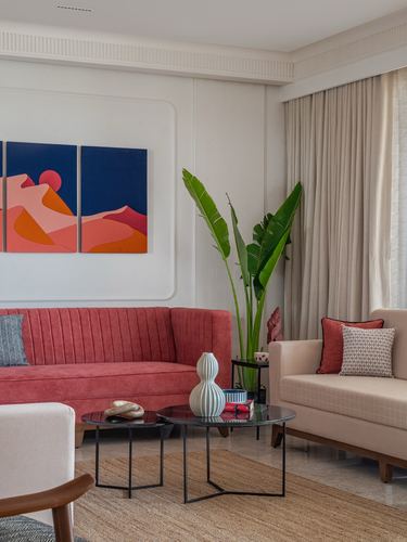 Living room with coral velvet sofa, beige sofa, round black coffee tables, and desert-themed artwork