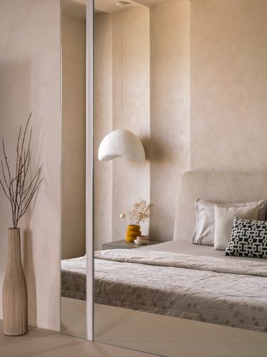 Neutral limewash bedroom with dome pendant light, upholstered bed and mirrored wardrobe reflection