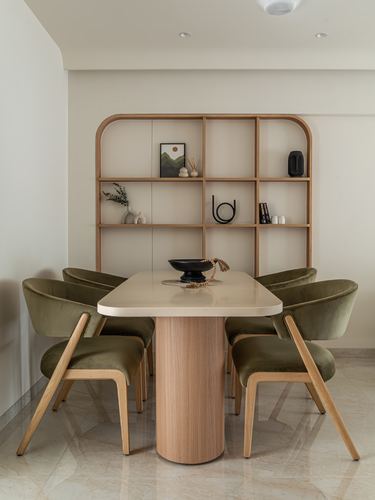 Dining table with olive velvet chairs beneath an arched wooden display shelf
