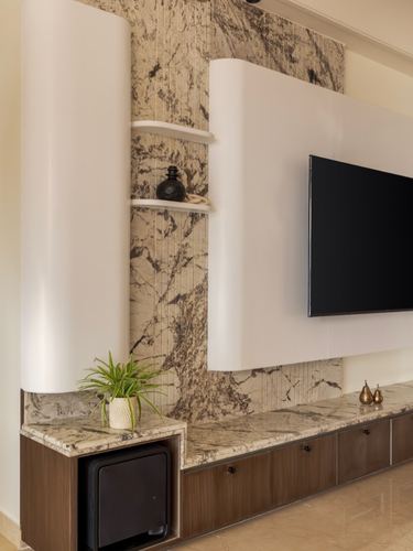 Curved white TV unit panels flanking a stone-clad niche with shelf display and wooden storage below