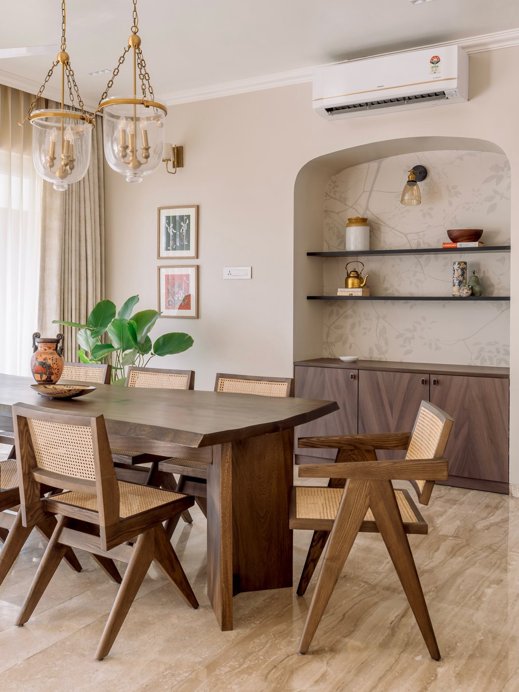 Dining room with cane Pierre Jeanneret-style chairs, live-edge table, and arched display niche
