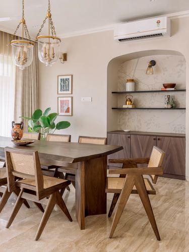 Dining room with cane Pierre Jeanneret-style chairs, live-edge table, and arched display niche