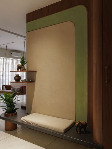 Curved green and beige wall niche with bench seat and brass elephant figurine in foyer