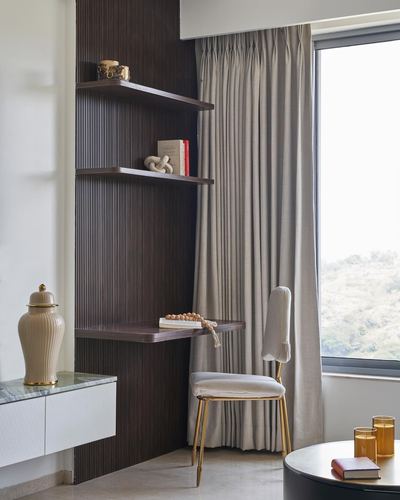 Corner study nook with fluted wood panel, floating shelves, small desk and gold chair by window