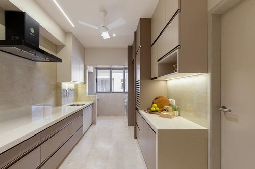 Narrow beige galley kitchen with chimney hood, ceiling fan, and daylit window at end