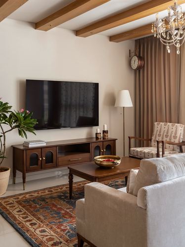 Living room with wooden tv console, patterned rug, beamed ceiling, and beige sofa