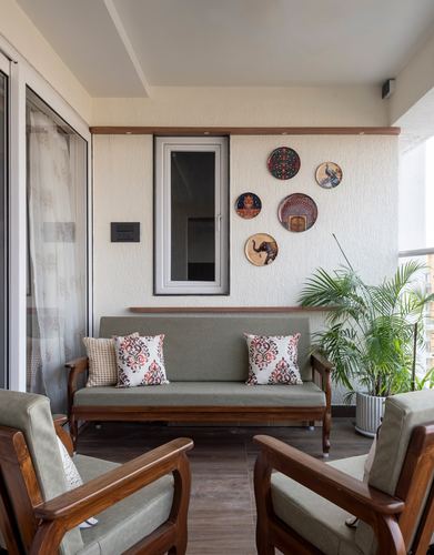 Balcony seating with teak sofa, chairs, and a wall arrangement of decorative plates