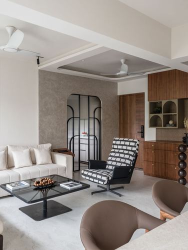 Living room with cream sofa, patterned armchair, and arched glass door in taupe wall