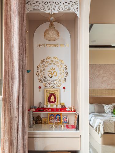 Arched pooja unit with om mandala decal, deity frames, and carved white jali canopy overhead