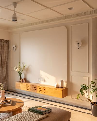 Cream-toned living room with paneled walls and a floating wood TV console lit by afternoon light
