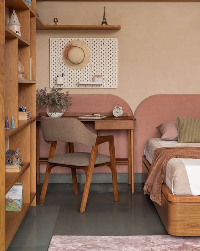 Study desk and chair beside a terracotta arched-headboard bed in a warm-toned bedroom