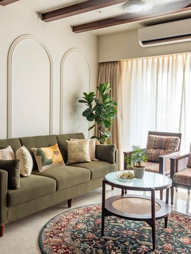 Living room with olive sofa, arched wall niches, cane chairs, and round patterned rug