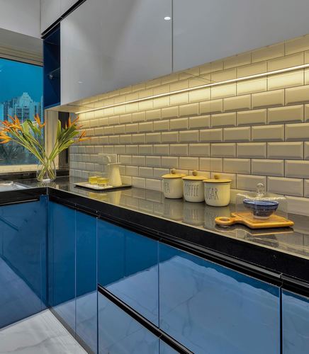 Kitchen corner with glossy blue cabinets, black countertop, beveled tile backsplash, and ceramic canisters
