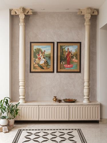 Two carved ancestral columns flank a niche with framed deity art above a fluted console