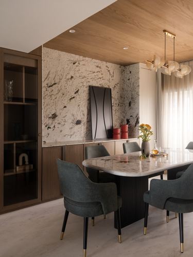 Dining room with marble-top table, green velvet chairs, textured feature wall and wood ceiling drop
