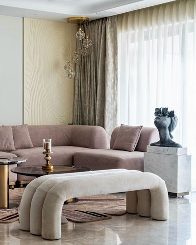 Living room with pink sectional, boucle bench, bubble chandelier and marble sculpture plinth