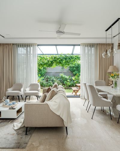 Beige living and dining room opening through glass doors to a green courtyard garden