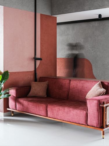 Maroon sofa with cane side panel against terracotta and grey color-blocked walls