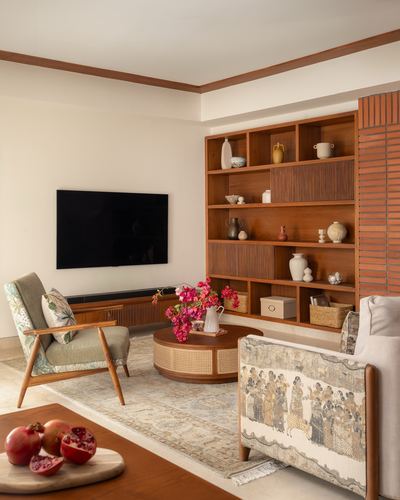 Living room with wooden shelving, cane coffee table, patterned armchairs and mounted tv