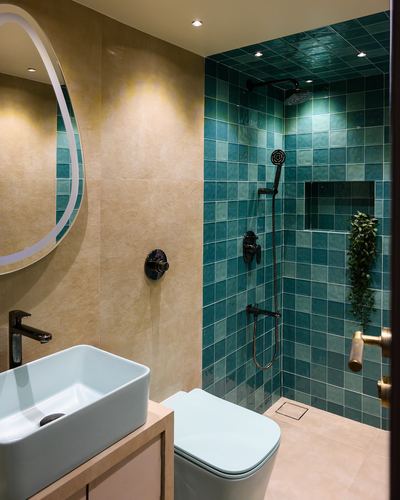Bathroom with teal tiled shower, beige stone walls, oval mirror and mint wall-hung toilet