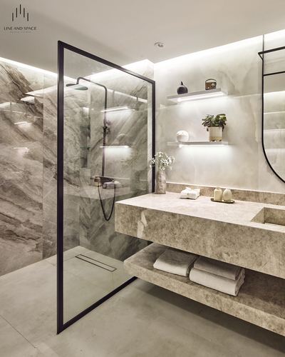 Modern marble-look bathroom with glass shower partition, floating stone vanity, and backlit shelving