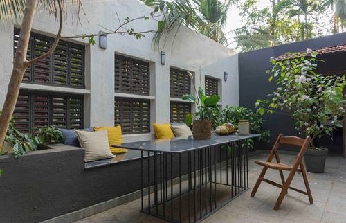 Outdoor courtyard seating with slatted wood windows, black bench and stone table