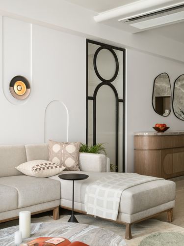 Beige sectional sofa beside a black-framed circular glass door and wooden console with mirrors