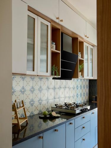 Kitchen with white upper cabinets, blue lower cabinets, black countertop, and patterned tile backsplash
