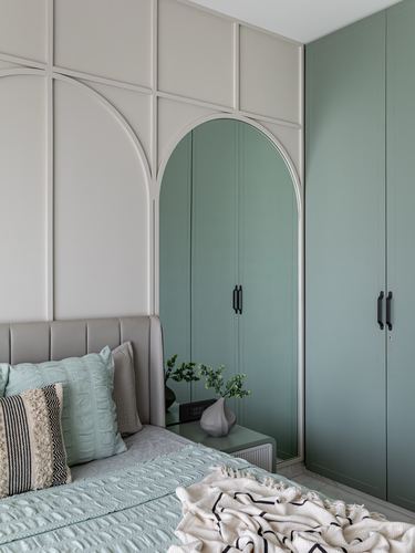 Bedroom corner with sage green arched wardrobe doors and channel-tufted headboard with mint bedding