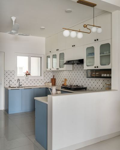 White and blue kitchen with patterned tile backsplash and brass pendant lighting over the hob