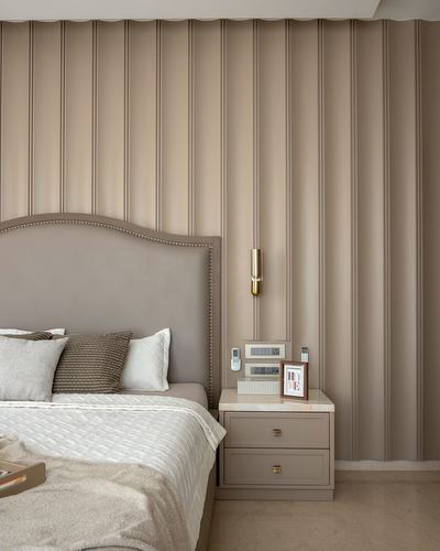 Beige bedroom corner with fluted wall panelling, upholstered headboard and marble-top nightstand