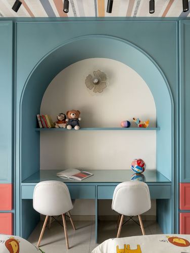 Blue arched niche with built-in desk, two white chairs, and a shelf of toys for a child's study corner.