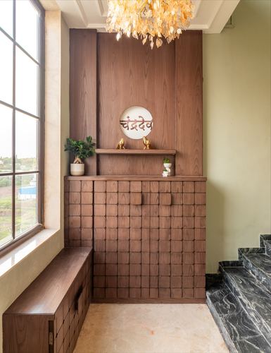 Wooden textured foyer wall with circular Hindi name plate, brass birds, and marble staircase edge