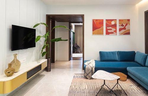 Living room with teal sectional, marble floor, triptych art and TV console with plant