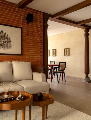 Living room with exposed brick wall, wooden beam ceiling, beige sofa and view to dining area
