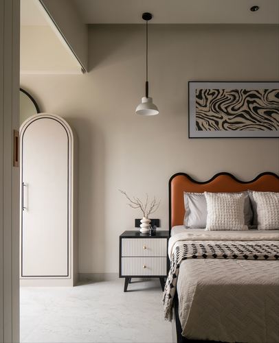 Bedroom corner with scalloped orange headboard, arched wardrobe, and pendant light