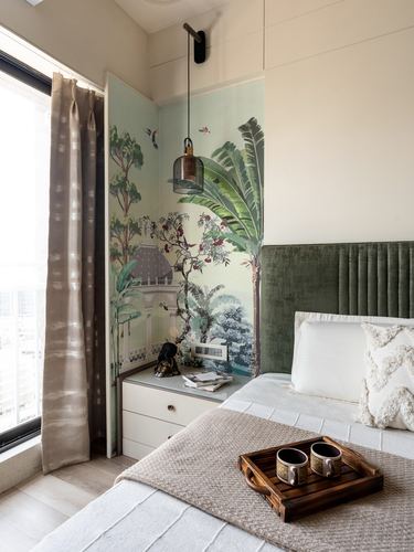 Bedroom corner with tropical mural wallpaper, pendant light, white nightstand, and green velvet headboard bed