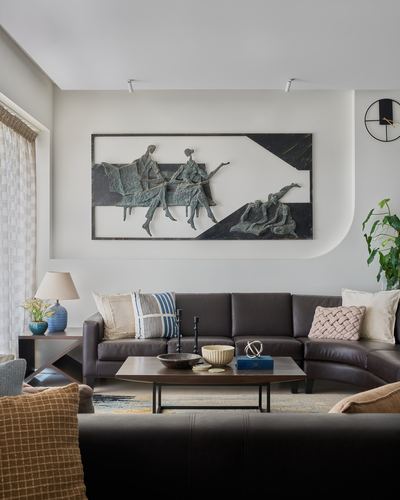 Living room with brown leather sectional, wooden coffee table, and bronze figurative wall art